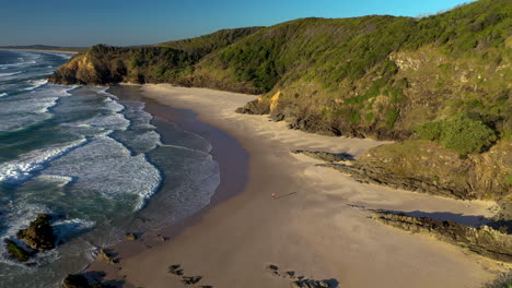 Cinematic-drone-shot-flying-over-trees-towards-sandy-beach-at-Broken-Head-coast-near-Byron-Bay