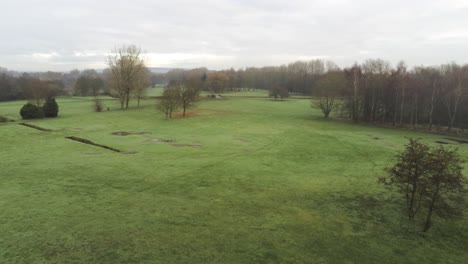 Aerial-view-overcast-frosty-green-golf-course-country-club-fairway-pull-back