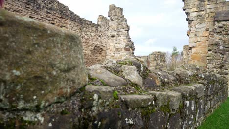 Ancient-Basingwerk-abbey-abandoned-historical-landmark-building-stone-walls-low-closeup-dolly-right