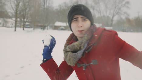 Woman-Wearing-Red-Winter-Clothes-Throwing-Snowball-Towards-The-Camera-On-A-Cold-Winter-Day---Handheld,-Medium-Shot