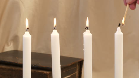 Advent-candlesticks-are-lit-by-hand-with-match,-close-up-slider-shot