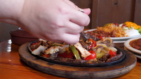 Hand-uses-fork-to-fill-taco-with-sizzling-fajita-meat,-close-up-slow-motion-slider-push-4K