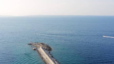 Barcos-Navegando-En-Aguas-Tranquilas-Del-Océano-Por-La-Costa-Rocosa-Del-Muelle-Artificial-En-Veli-Losinj,-Croacia