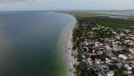 Aerial-view-Moving-shot,-Scenic-view-of-Houses-and-building-near-the-beach-in-the-Isla-Holbox-In-Mexico,-Grassland-and-blue-sky-in-the-background