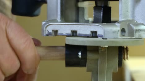 Close-up-of-making-bolt-threads-on-wooden-dowel-using-electric-router-and-jig
