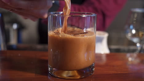 Barkeeper-Gießt-Kaffee-Schokoladen-Cocktail-über-Eis-Im-Glas,-Slider-Nahaufnahme-Zeitlupe-4k