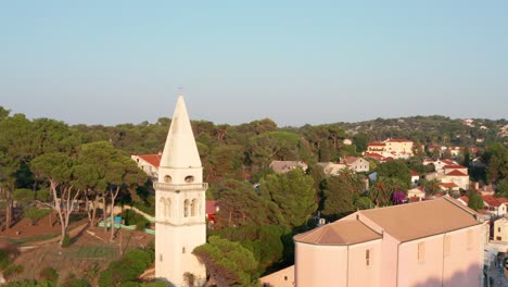 Mid-height-aerial-shot-circling-around-a-church-tower-in-Veli-Losinj,-Croatia