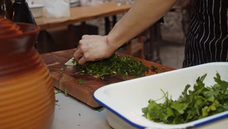 Close-up-on-chef-hands-cutting-green-leaf-salad-on-wooden-cut-board-on-outdoor-catering-table