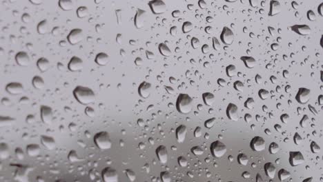 Extreme-closeup-of-large-raindrops-on-window-with-grey-background