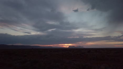 Slow-panning-shot-across-horizon-during-a-stormy-desert-sunset-at-twilight