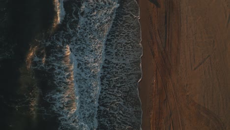 Top-view-of-ocean-waves-during-sunset-with-one-person-walking-by