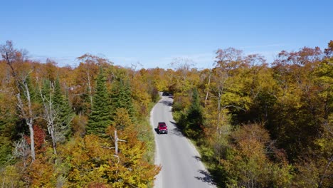 Aerial,-Cars-Driving-on-Remote-Road-Surrounded-by-Autumn-Landscape
