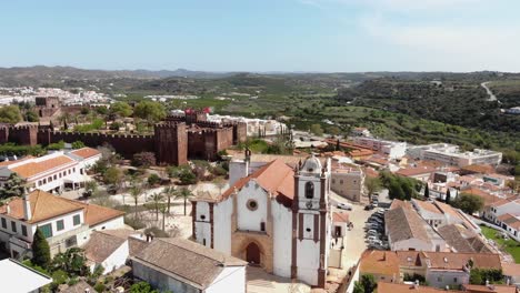 Pull-away,-4k-aerial-drone-footage-revealing-surrounding-area-around-the-historical-Silves-Cathedral-of-the-tourist-destination-town-of-Silves,-Portugal