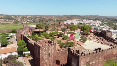 Portuguese-Flag-waving-atop-the-Castle-of-Silves-in-Algarve---Ascending-Panoramic-Aerial-shot
