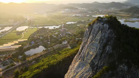 4k-Top-down-Aerial-footage-of-carved-Buddha-Image-made-from-Gold-on-a-cliff-at-Khao-Chee-Chan,-Pattaya,-Thailand
