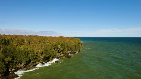 Aerial-Backwards-Reveal:-Waves-Crash-on-Rocky-Coast-of-Lake-Michigan,-Cave-Point-County-Park-in-Autumn