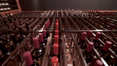 Various-bottles-of-wine-stored-in-a-wine-rack,-winery-storage,-slider-up-angle-HD
