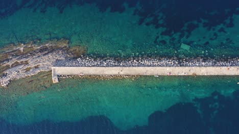 Beautiful-rocky-pier-on-Mediterranean-island-coastline,-aerial-top-down