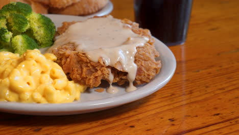 Chicken-fried-steak-with-gravy-macaroni-and-cheese-broccoli-on-white-dish,-plated-comfort-food,-slider-4K