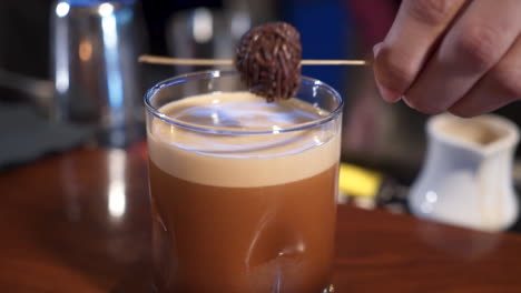 Bartender-tops-off-drink-with-skewered-chocolate-truffle,-close-up-slider-slow-motion-4K
