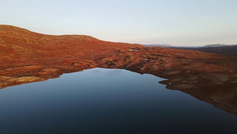 Drone-footage-of-calm-mountain-lake-at-sunset-in-Southern-Norway