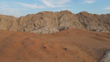 Drone-View-of-Desert-Safar,-offroading-in-Sharjah's-Mleiha-desert,-group-of-4x4-vehicles-rides-on-desert-dunes,-Mleiha-Mountains,-4k-Footage