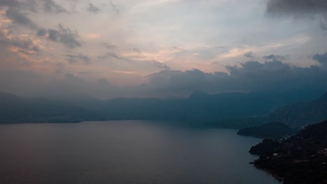 Drone-aerial-hyperlapse-of-a-beautiful-sunset-behind-the-clouds-in-Lake-Atitlan,-Guatemala