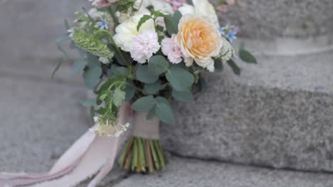 wedding-bouquet-with-vibrant-flowers-with-pink-velvet-band-on-stone-stairs
