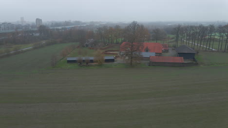 Aerial-dolly-of-small-farm-in-rural-area-with-mist-in-the-background