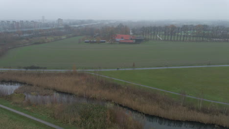 Fliegen-Zu-Einem-Kleinen-Bauernhof-In-Den-Ländlichen-Niederlanden-Mit-Einem-Nebligen-Hintergrund