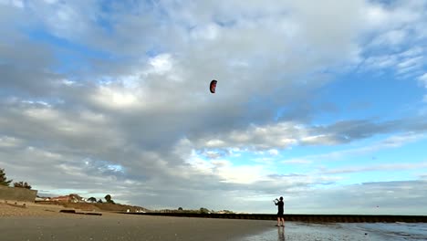 Man-flying-a-power-kite-on-the-beach-making-large-firgures-of-eight