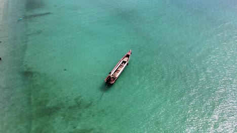 4k-aerial-drone-footage-circling-a-long-tail-boat-anchored-off-the-coast-of-Ko-Larn-Island,-Thailand