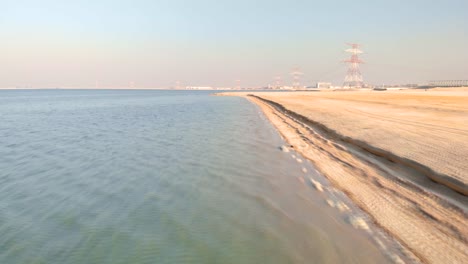 Fast-low-flying-drone-view-along-barren-desert-beach,-UAE