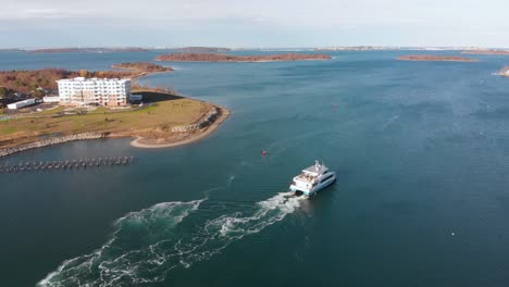 Daytime-drone-view-of-a-water-shuttle-getting-underway-on-the-harbor,-pulling-away-from-the-dock