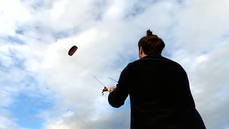 A-man-flying-a-power-kite-high-up-in-a-cloudy-sky