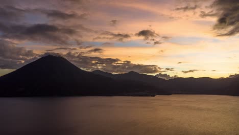 Drone-aerial-hyperlapse,-volcanic-landscape-during-stunning-sunset-in-Lake-Atitlan,-Guatemala
