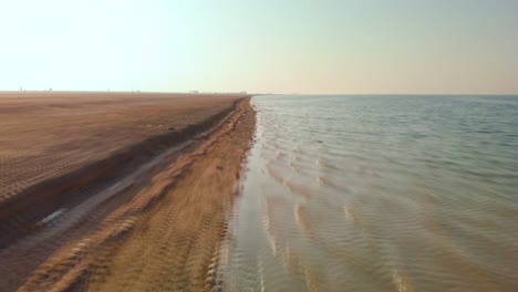Drone-speeding-low-along-desolate-desert-coastline,-Abu-Dhabi,-UAE