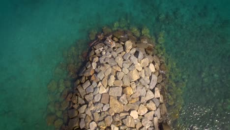 Birds-eye-view-of-a-rock-breakwater-on-the-green-and-calm-Caribbean-Sea