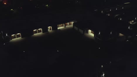 High-school-at-night,-over-buildings-and-campus,-rising-aerial-drone-view