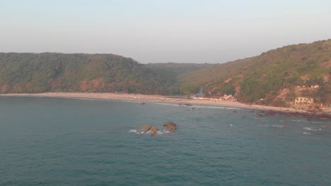 Arabian-Sea-washing-up-on-Arambol-shore-in-Goa,-India---Aerial-wide-fly-over-shot