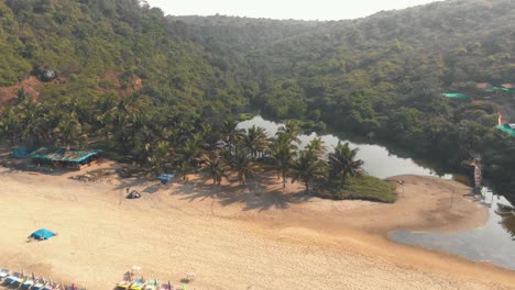 Sweet-Water-lake-near-ocean-shore-in-Arambol-beach-resort,-in-Goa,-India---Aerial-Low-angle-Orbit