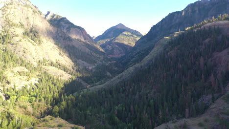 Luftdrohne-Enthüllen-Die-Wunderschöne-Ouray-Colorado-Mountain-Range-Und-Autos,-Die-Auf-Dem-Highway-550-Fahren,-Umgeben-Von-Dichten-Pinienwäldern-Und-Stromleitungen-In-Den-Rocky-Mountains