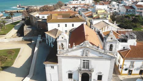 Top-view-of-Church-of-Santa-Maria-de-Lagos-and-reveal-of-Atlantic-coast---Aerial-Fly-over-Reveal-shot
