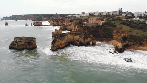Algarve-rocky-eroded-cliffs-in-the-Atlantic-coast-in-Student-Beach-In-Lagos,-Portugal---Aerial-Orbit