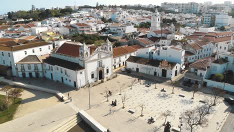 Church-of-Santa-Maria-de-Lagos-in-the-Old-town-Square,-in-Algarve,-Portugal---Aerial-Panoramic-Ascending-shot