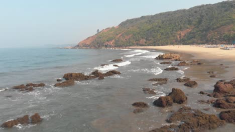Arambol-rocky-idyllic-shoreline-in-North-Goa,-India---Aerial-low-angle-fly-over-shot