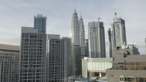 Forward-aerial-shot-of-Kuala-Lumpur-skyline-and-girl-by-rooftop-pool