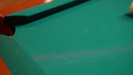Slow-Motion-Billiards-yellow-striped-9-ball-shot-in-corner-pocket-on-pool-table-with-green-felt-and-brown-pockets-using-the-cue-ball-and-back-spin-or-draw-Close-Up-with-Red-Spinning-Dots