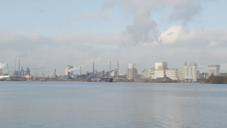 Wide-shot-of-polluting-industrial-buildings-standing-on-river-shore