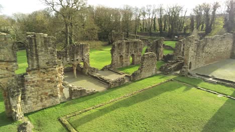 Basingwerk-abbey-landmark-medieval-abandoned-Welsh-ruins-Aerial-view-right-pan-low-angle